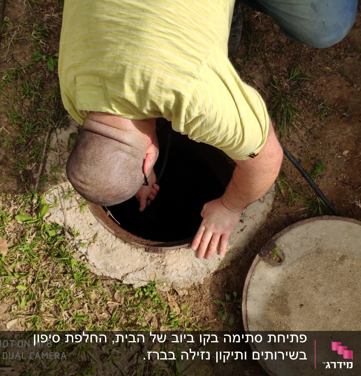 אדם בודק פתח ביוב עם מכסה פתוח